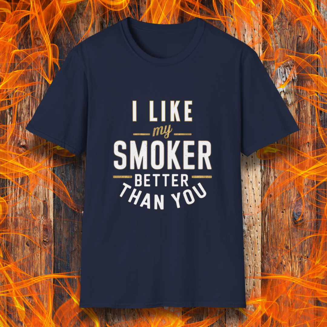 Navy  T-shirt featuring a witty BBQ-themed design. The bold text reads 'I Like My Smoker Better Than You' in a mix of white and gold lettering, with decorative lines adding emphasis. A perfect shirt for grill masters and smoking enthusiasts with a sense of humor.