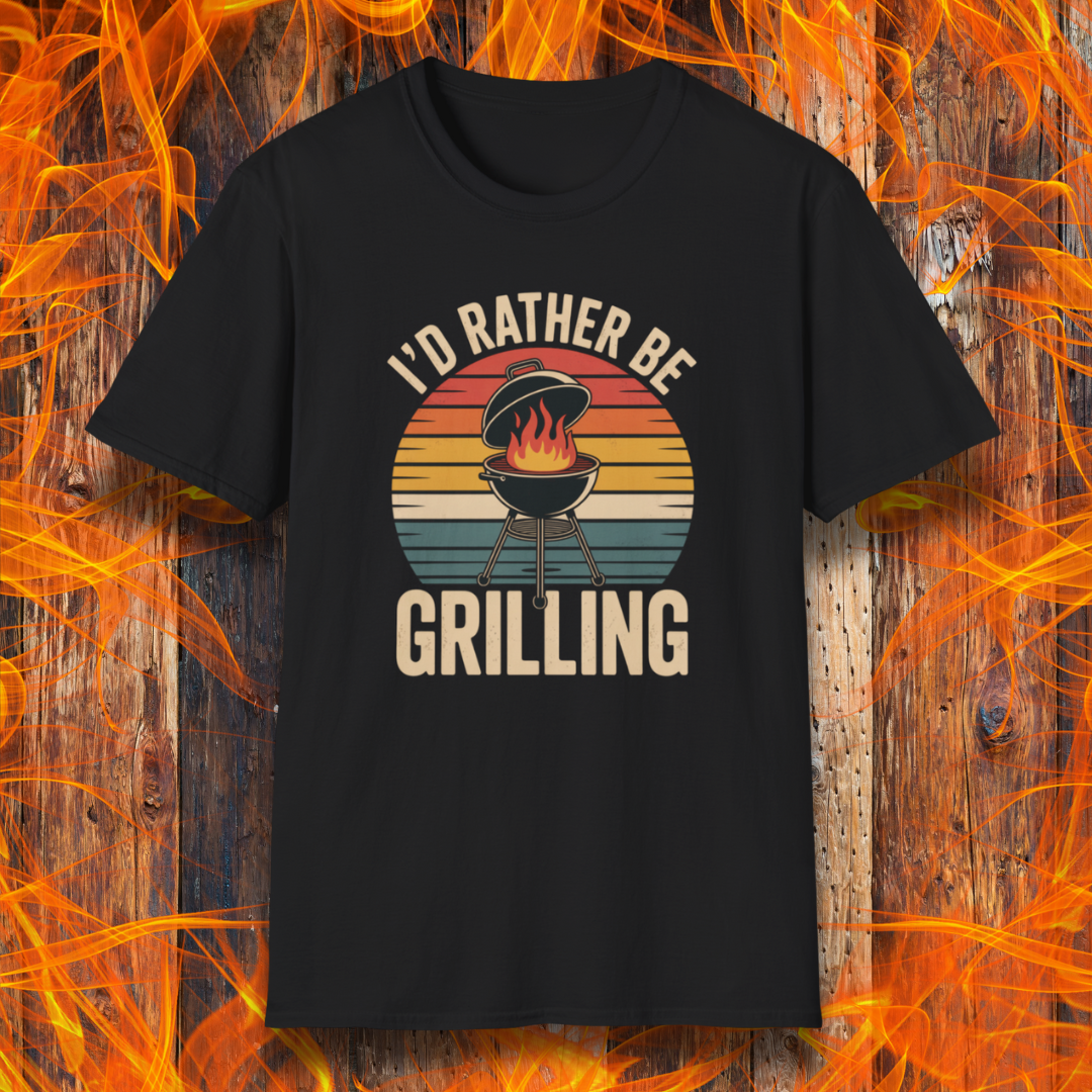 Black t-shirt with 'I'd Rather Be Grilling' graphic on a wooden background with flames.