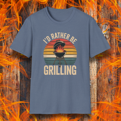 Heather Indigo t-shirt with 'I'd Rather Be Grilling' graphic on a wooden background with flames.