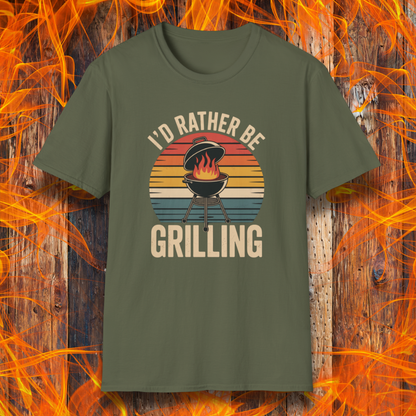 Military Green t-shirt with 'I'd Rather Be Grilling' graphic on a wooden background with flames.