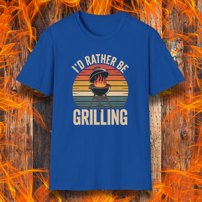 Royal Blue t-shirt with 'I'd Rather Be Grilling' graphic on a wooden background with flames.