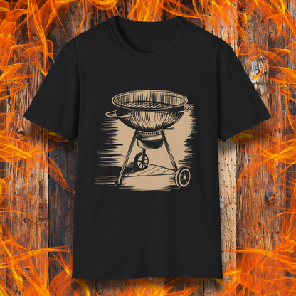 Black T-shirt featuring a vintage-style beige sketch of a classic charcoal kettle grill. The illustration has a hand-drawn, rustic look with shading lines that add depth and texture. The background consists of a wooden surface with bright orange flames, enhancing the fiery BBQ theme.