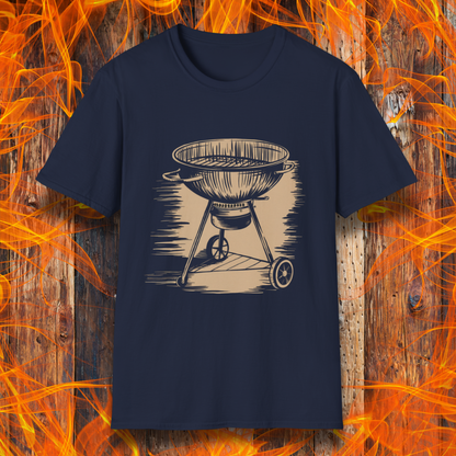 Navy T-shirt featuring a vintage-style beige sketch of a classic charcoal kettle grill. The illustration has a hand-drawn, rustic look with shading lines that add depth and texture. The background consists of a wooden surface with bright orange flames, enhancing the fiery BBQ theme.