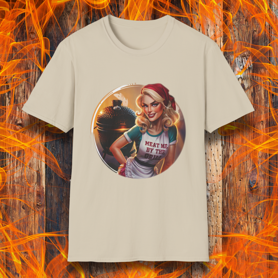 Sand t-shirt featuring a vintage-inspired pin-up style woman in front of a charcoal grill, wearing an apron that reads 'Meat Me By The Grill.