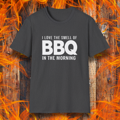 Dark Heather t-shirt with the phrase 'I Love the Smell of BBQ in the Morning' in bold white text, displayed against a fiery wooden background