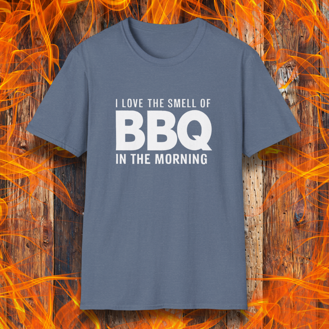 Heather Indigo t-shirt with the phrase 'I Love the Smell of BBQ in the Morning' in bold white text, displayed against a fiery wooden background