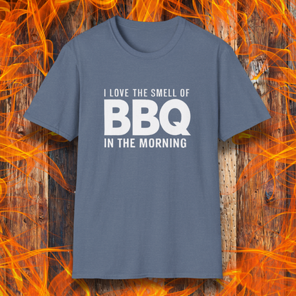Heather Indigo t-shirt with the phrase 'I Love the Smell of BBQ in the Morning' in bold white text, displayed against a fiery wooden background
