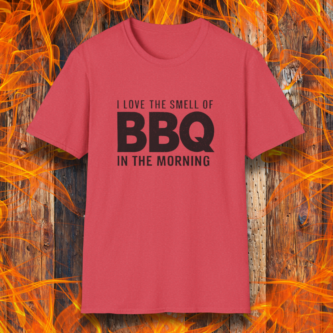 Heather Red t-shirt with the phrase 'I Love the Smell of BBQ in the Morning' in bold white text, displayed against a fiery wooden background