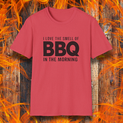 Heather Red t-shirt with the phrase 'I Love the Smell of BBQ in the Morning' in bold white text, displayed against a fiery wooden background