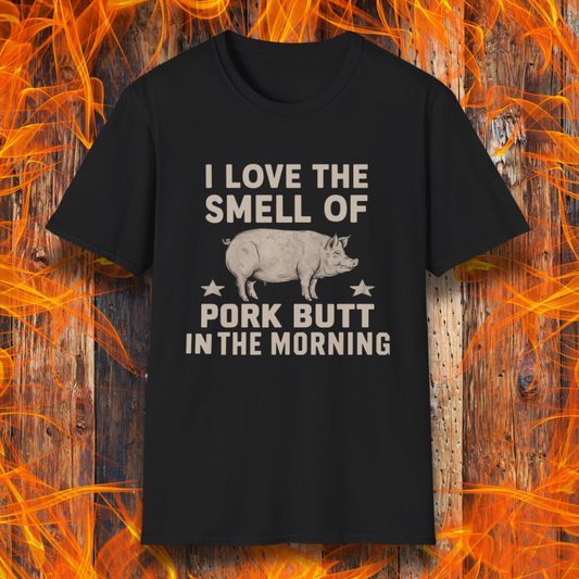 Black T-shirt with bold beige text reading 'I Love the Smell of Pork Butt in the Morning,' featuring a vintage-style pig illustration and star accents. Perfect for BBQ enthusiasts and pitmasters!