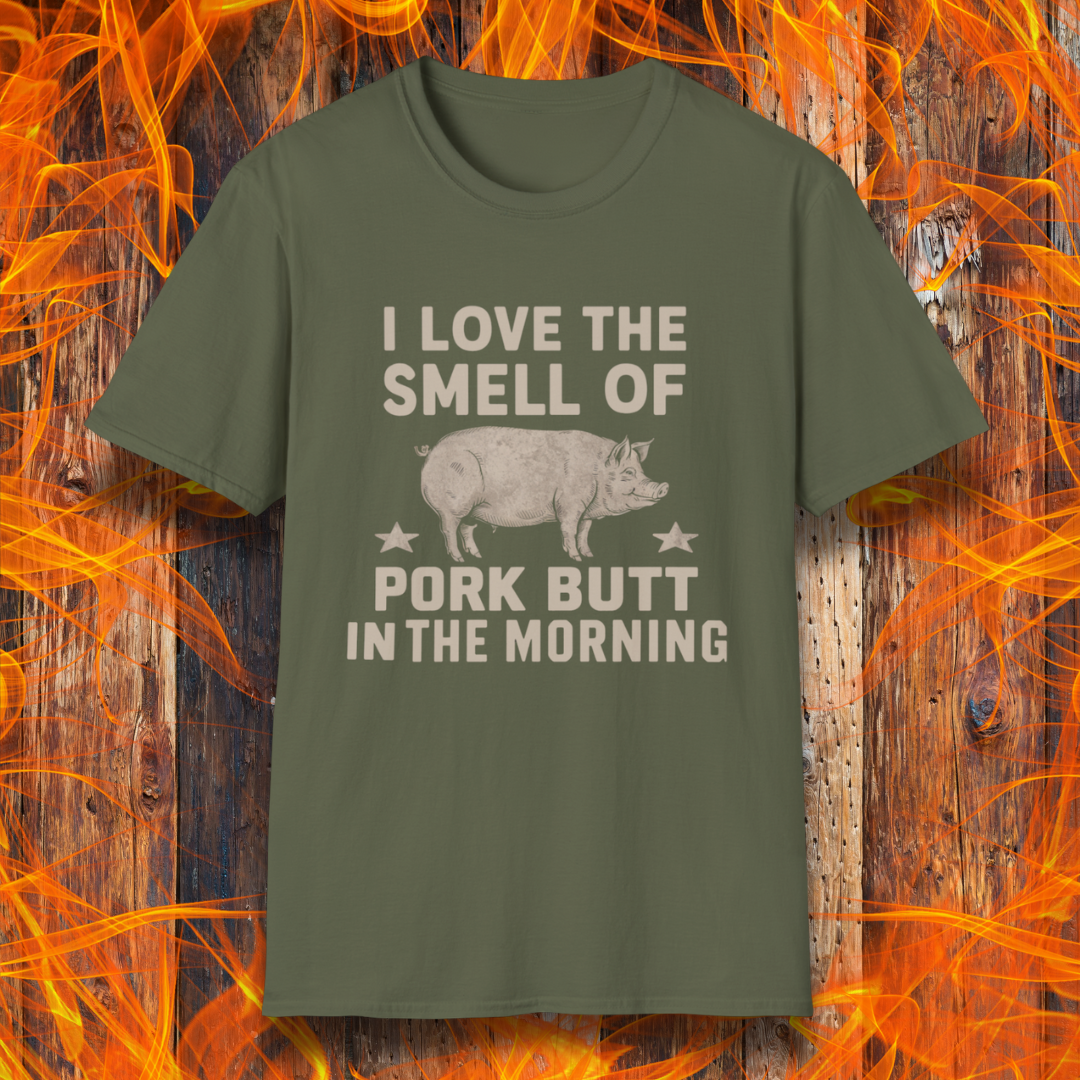 Military Green T-shirt with bold beige text reading 'I Love the Smell of Pork Butt in the Morning,' featuring a vintage-style pig illustration and star accents. Perfect for BBQ enthusiasts and pitmasters!