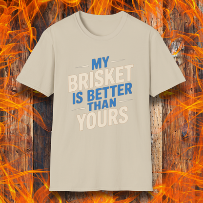 Sand T-shirt featuring a bold BBQ-themed design that reads 'MY BRISKET IS BETTER THAN YOURS' in cream and blue block lettering with accent lines. A perfect shirt for competitive grillers and brisket masters who love to show off their smoking skills.