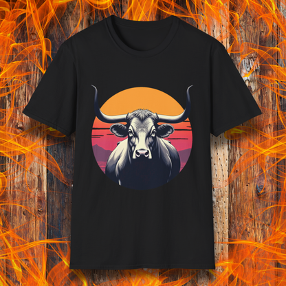 Black T-shirt featuring a striking design of a longhorn bull staring forward with an intense gaze. The bull is set against a circular backdrop of a sunset with warm orange, red, and pink hues, along with silhouetted mountains in the background. The design conveys strength, confidence, and a bold Western aesthetic, appealing to BBQ and cattle enthusiasts.