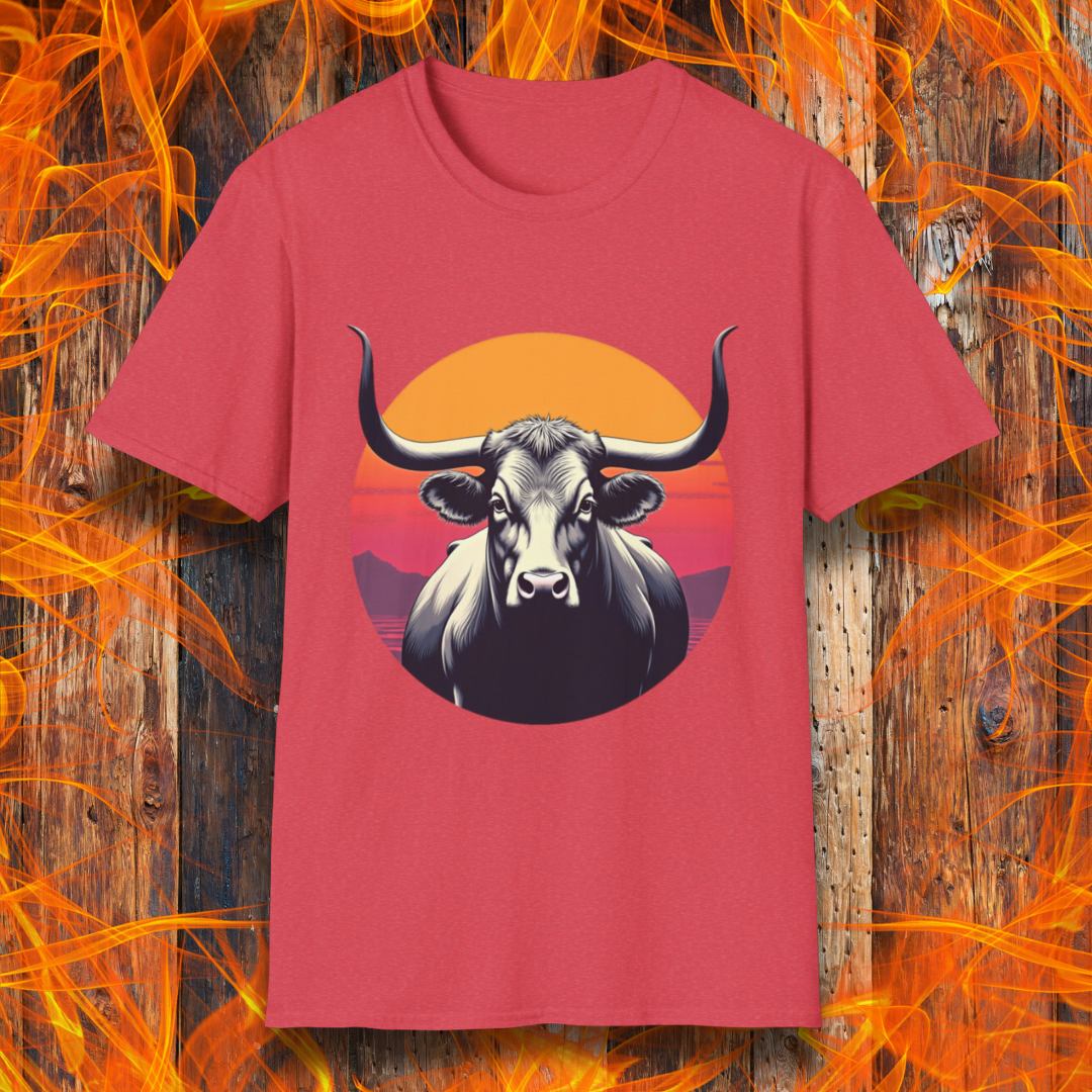 Heather Red T-shirt featuring a striking design of a longhorn bull staring forward with an intense gaze. The bull is set against a circular backdrop of a sunset with warm orange, red, and pink hues, along with silhouetted mountains in the background. The design conveys strength, confidence, and a bold Western aesthetic, appealing to BBQ and cattle enthusiasts.