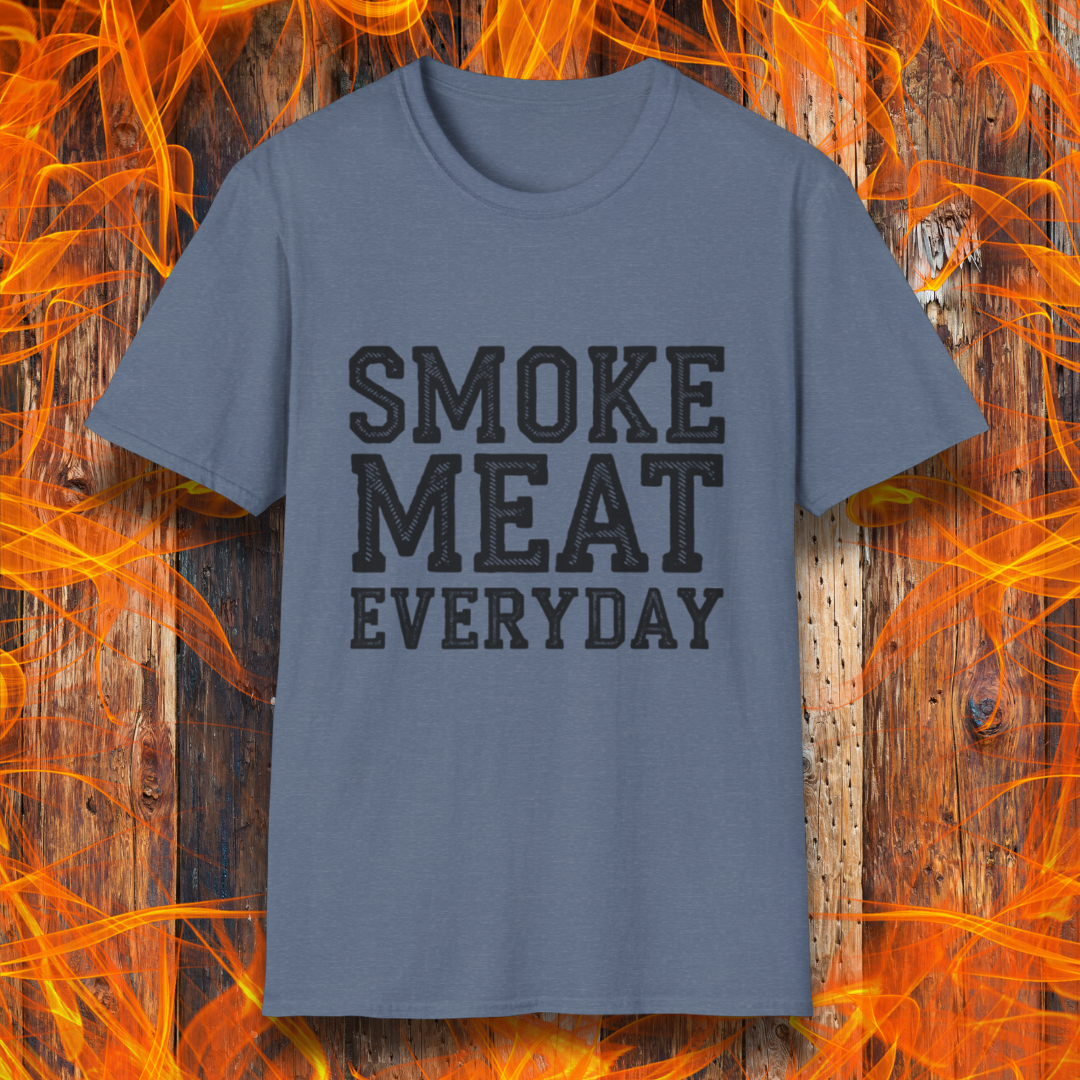 Heather Indigo T-shirt featuring bold, white, distressed-text lettering that reads "SMOKE MEAT EVERYDAY." The shirt is displayed against a fiery wooden background, reinforcing the BBQ and grilling theme.