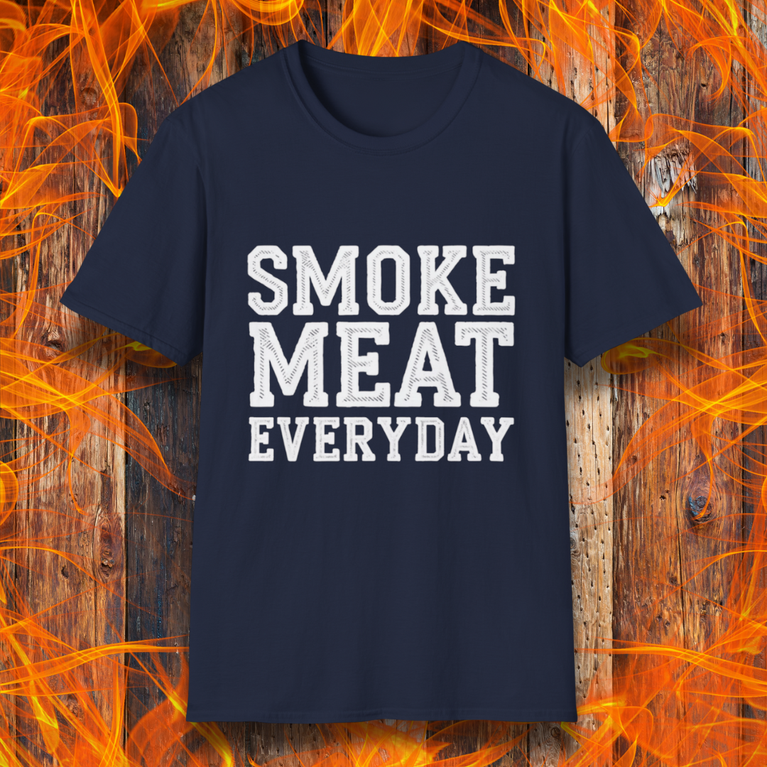 Navy T-shirt featuring bold, white, distressed-text lettering that reads "SMOKE MEAT EVERYDAY." The shirt is displayed against a fiery wooden background, reinforcing the BBQ and grilling theme.
