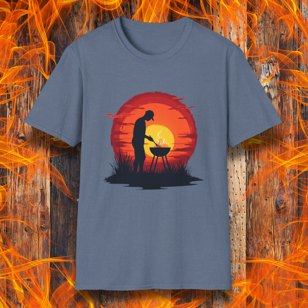 Heather Indigo  T-shirt featuring a vibrant design of a silhouetted man grilling in front of a large, glowing sunset. The sunset has warm hues of red, orange, and yellow, creating a striking contrast against the dark background. The scene is framed with grass and subtle clouds, giving it an outdoorsy, serene BBQ vibe.