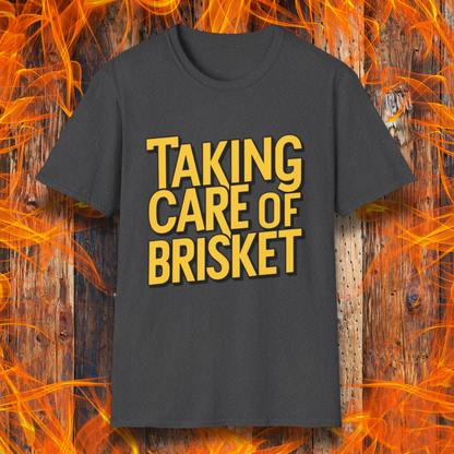 Dark Heather T-shirt with bold yellow text reading 'Taking Care of Brisket,' a fun BBQ-themed design inspired by classic rock and grilling culture.