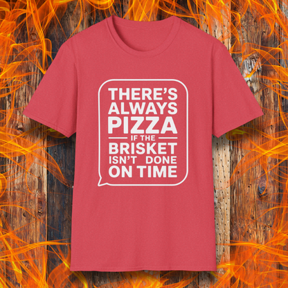 Heather Red T-shirt featuring bold white text in a speech bubble that reads "There’s Always Pizza If the Brisket Isn’t Done on Time," displayed over a wooden background with flames — a humorous shirt for BBQ fans who know the struggle of low-and-slow cooking.