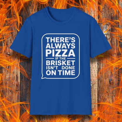 Royal Blue T-shirt featuring bold white text in a speech bubble that reads "There’s Always Pizza If the Brisket Isn’t Done on Time," displayed over a wooden background with flames — a humorous shirt for BBQ fans who know the struggle of low-and-slow cooking.