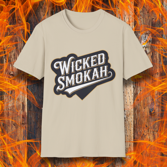 Sand T-shirt featuring a bold, vintage-style design that reads "Wicked Smokah" in stylized typography, resembling a sports team logo. The lettering has a mix of white and gold outlines, giving it a classic and rugged look. The shirt is displayed against a fiery wooden background, reinforcing the smoky BBQ theme.
